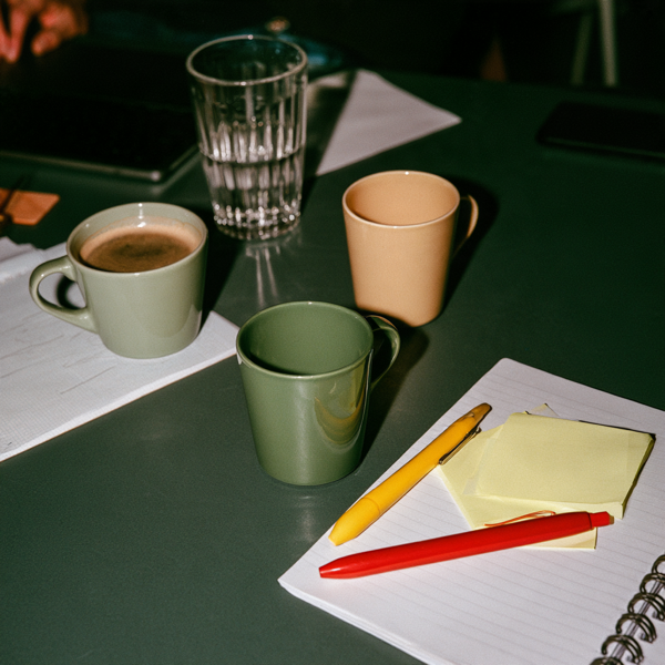 Mesa con tazas, lapiceras y post-its
